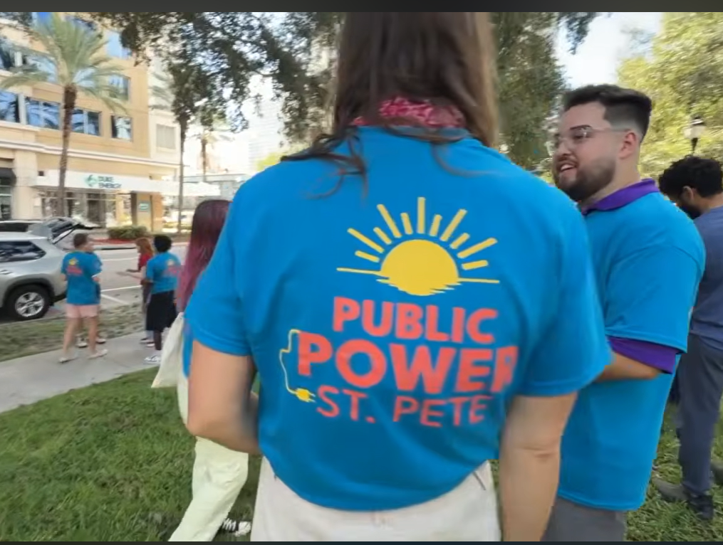 Back of woman's tshirt with Public Power St. Pete on it, standing across from Duke Energy office.